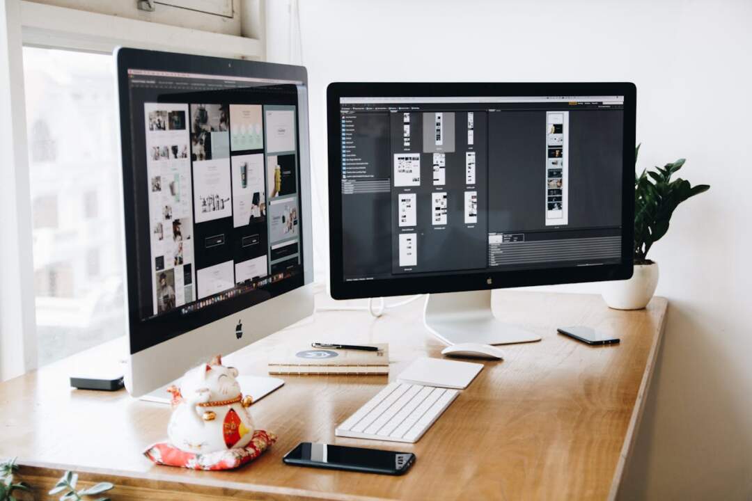 hero-contact A well-organized design workspace with dual monitors and design software on display.